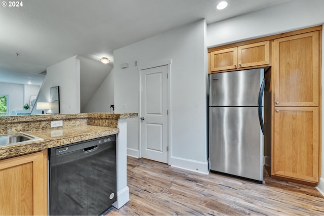 kitchen featuring sink, dishwasher, light hardwood / wood-style floors, vaulted ceiling, and stainless steel refrigerator