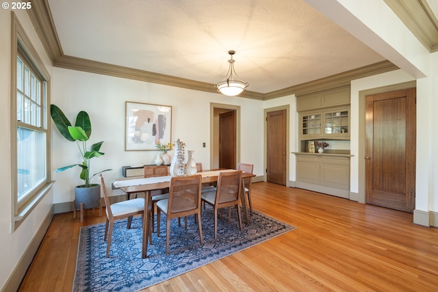 dining room featuring ornamental molding, a healthy amount of sunlight, and light hardwood / wood-style flooring