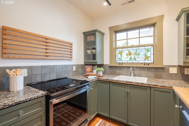 kitchen with stainless steel range with electric stovetop, sink, light stone counters, and backsplash