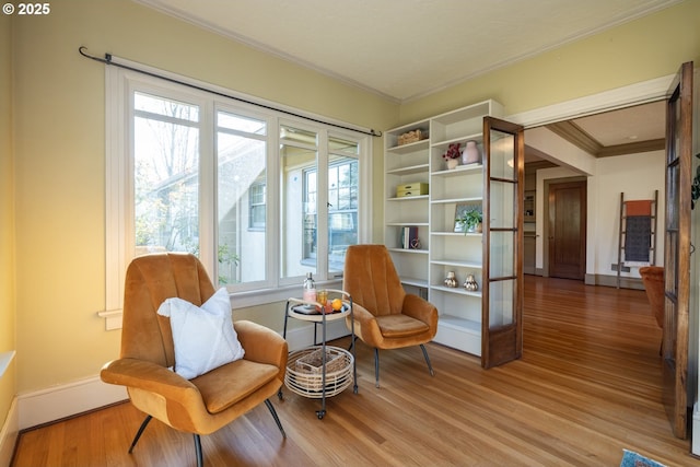 sitting room with ornamental molding and wood-type flooring