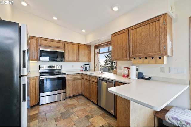 kitchen with sink, vaulted ceiling, kitchen peninsula, and stainless steel appliances