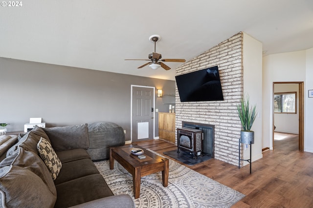 living room with ceiling fan, a wood stove, vaulted ceiling, and dark hardwood / wood-style floors