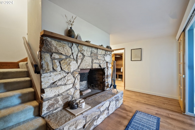 living room with a stone fireplace and light hardwood / wood-style flooring