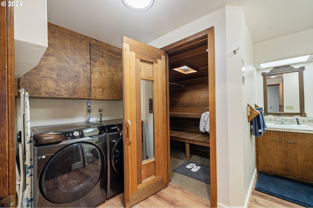 washroom featuring sink, light hardwood / wood-style floors, cabinets, and independent washer and dryer