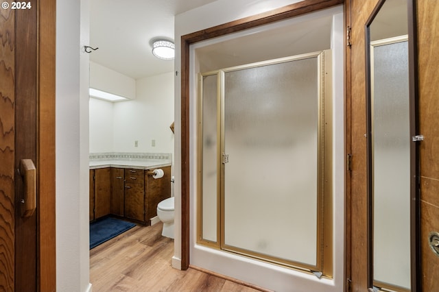 bathroom with a shower with door, hardwood / wood-style flooring, toilet, and vanity