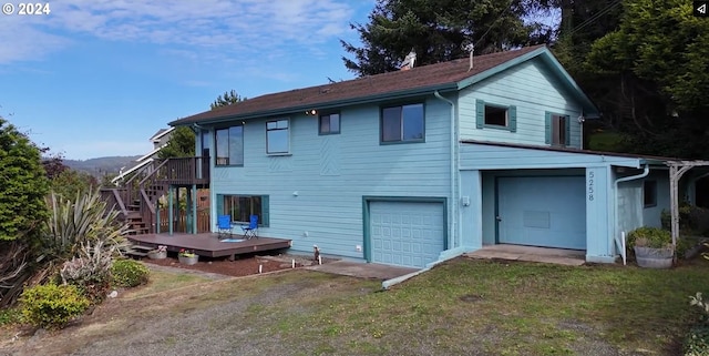 rear view of property featuring a yard, a wooden deck, and a garage