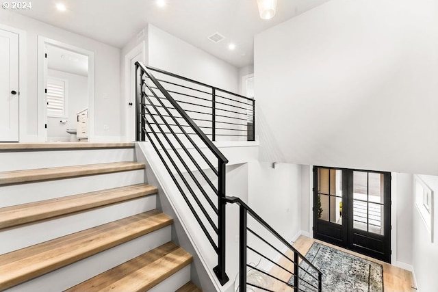 stairs with french doors and light wood-type flooring