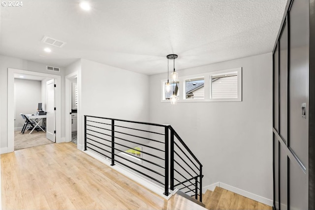 stairway with light hardwood / wood-style flooring and a textured ceiling