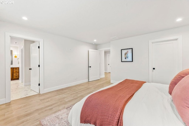 bedroom featuring connected bathroom and light hardwood / wood-style flooring