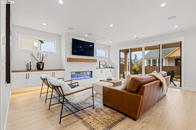 living room featuring a fireplace, brick wall, and light hardwood / wood-style flooring