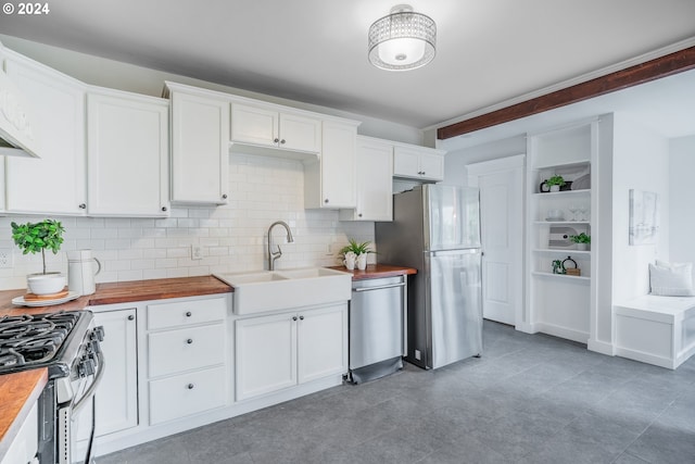 kitchen featuring stainless steel appliances, white cabinetry, butcher block counters, and sink