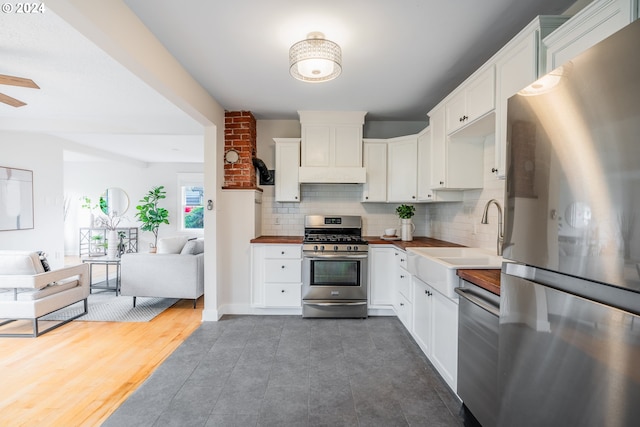 kitchen with backsplash, white cabinets, sink, appliances with stainless steel finishes, and dark hardwood / wood-style flooring