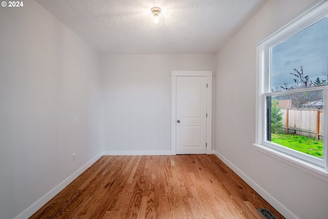 unfurnished room with a textured ceiling and light hardwood / wood-style floors