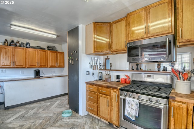 kitchen featuring stainless steel appliances, baseboards, and brown cabinetry