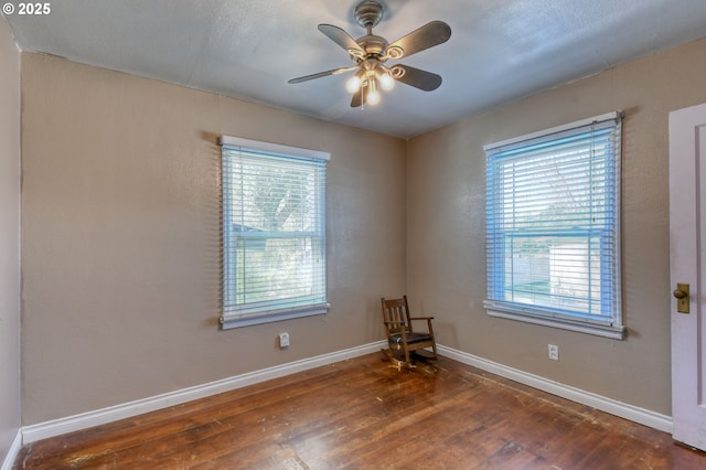 empty room featuring baseboards, wood-type flooring, and a ceiling fan