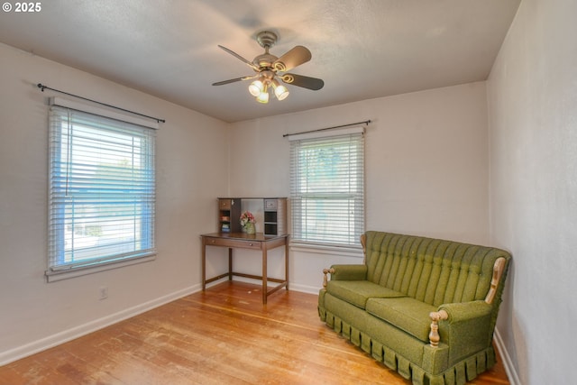 sitting room featuring baseboards, a ceiling fan, and wood finished floors