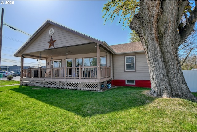 rear view of property featuring roof with shingles and a yard