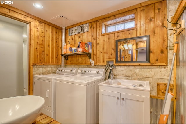 clothes washing area featuring independent washer and dryer, laundry area, and a sink