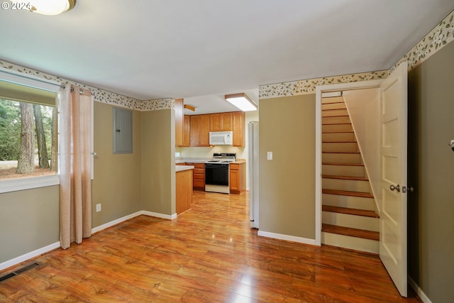 kitchen featuring white appliances, electric panel, and light wood-type flooring