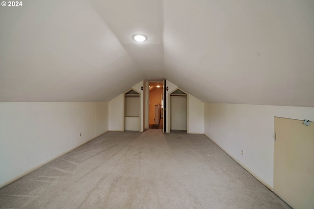 bonus room featuring vaulted ceiling and light carpet