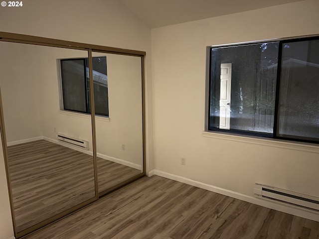 unfurnished bedroom featuring a closet, hardwood / wood-style floors, and baseboard heating