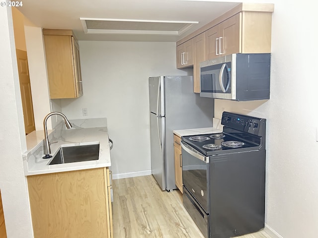 kitchen with black range with electric cooktop, light wood-type flooring, and sink