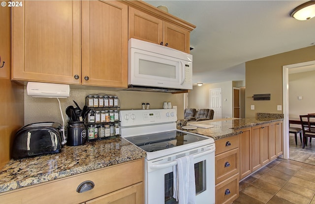 kitchen featuring light brown cabinetry, white appliances, and dark stone counters