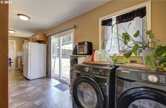 clothes washing area featuring light tile patterned floors and washer and dryer