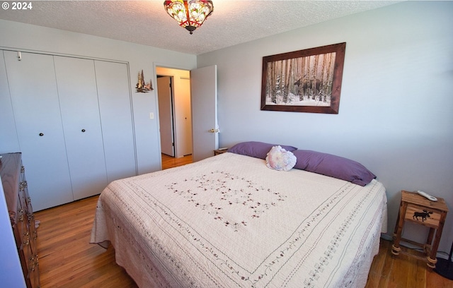 bedroom with a closet, wood-type flooring, and a textured ceiling