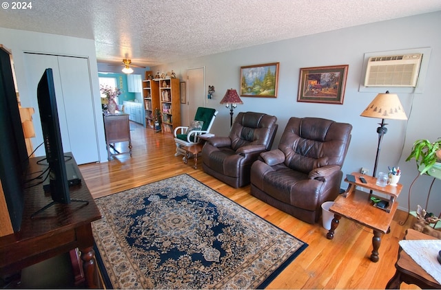 living room with ceiling fan, hardwood / wood-style flooring, a textured ceiling, and a wall mounted AC