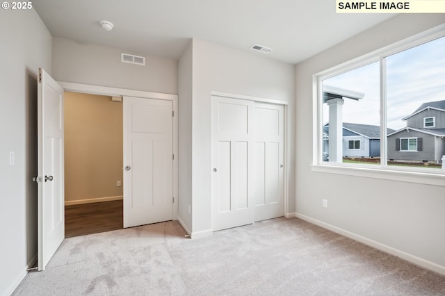 unfurnished bedroom featuring a closet, carpet flooring, visible vents, and baseboards