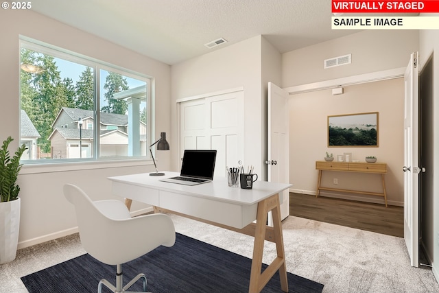 office space with baseboards, visible vents, and a textured ceiling