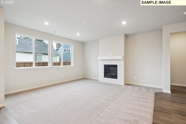 unfurnished living room featuring a tile fireplace, recessed lighting, carpet floors, visible vents, and baseboards