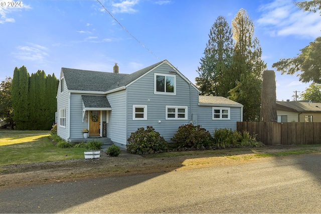 view of front of property featuring roof with shingles, fence, and a chimney