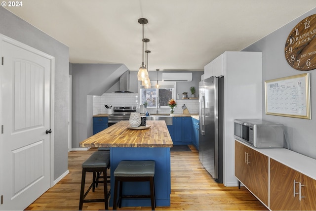 kitchen featuring a kitchen bar, a center island, an AC wall unit, stainless steel appliances, and blue cabinets