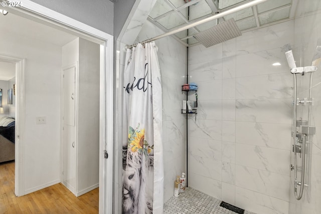 full bathroom featuring baseboards, a tile shower, and wood finished floors