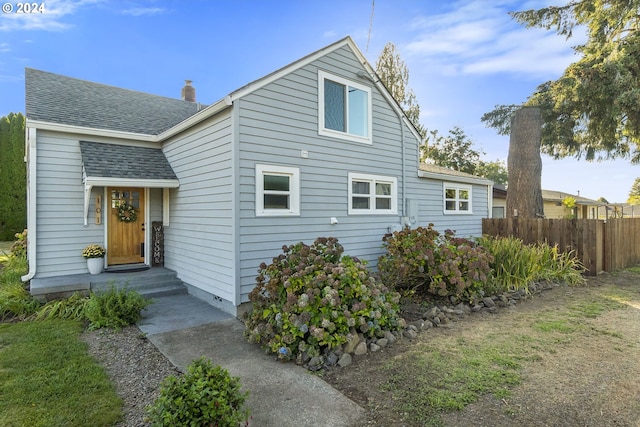 view of front of property with roof with shingles, fence, and a chimney