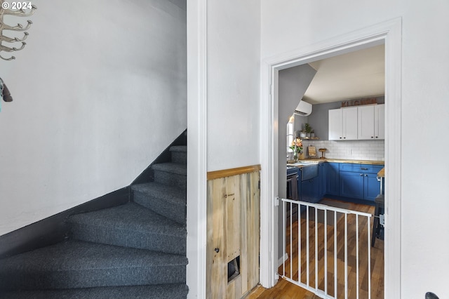 staircase featuring wood finished floors and a wall mounted air conditioner