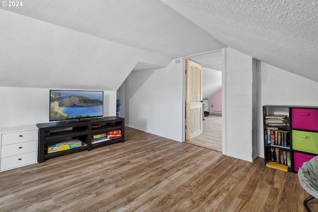 bonus room featuring vaulted ceiling, a textured ceiling, baseboards, and wood finished floors