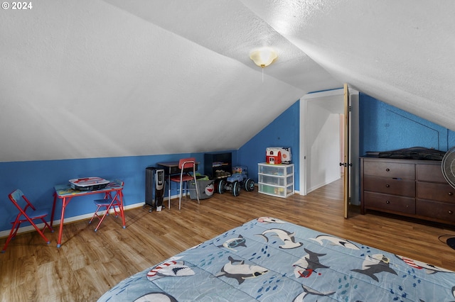 bedroom featuring a textured ceiling, vaulted ceiling, wood finished floors, and baseboards