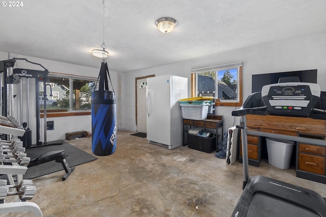 workout area featuring a textured ceiling, concrete flooring, and plenty of natural light