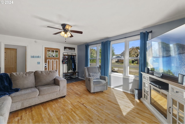 living area featuring light wood finished floors, baseboards, and a ceiling fan