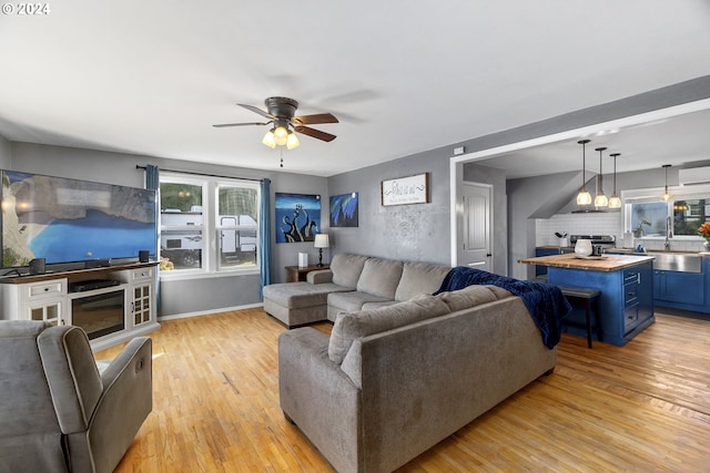 living area with a ceiling fan and light wood-type flooring