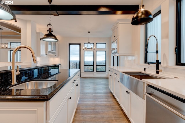 kitchen with pendant lighting, dishwasher, sink, white cabinetry, and light hardwood / wood-style flooring