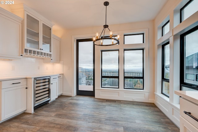 kitchen with pendant lighting, white cabinetry, wine cooler, and light hardwood / wood-style flooring