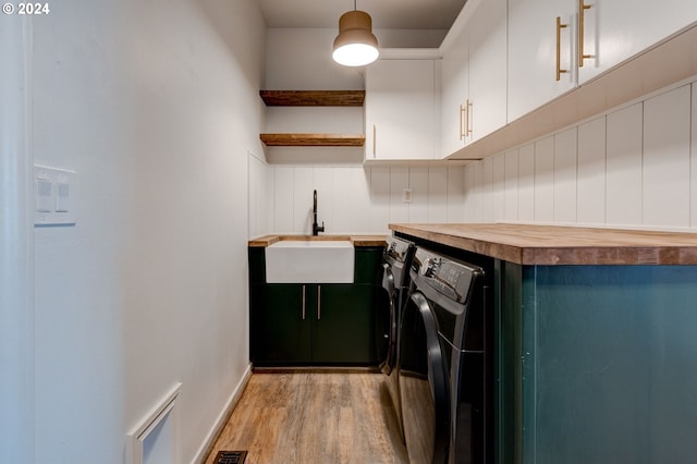 washroom featuring washer and clothes dryer, light wood-type flooring, cabinets, and sink