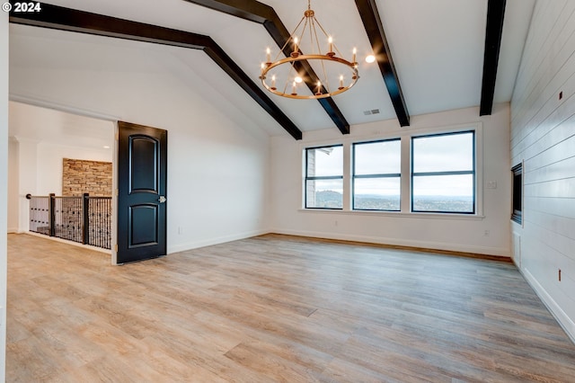 empty room with a chandelier, beamed ceiling, light wood-style flooring, baseboards, and high vaulted ceiling