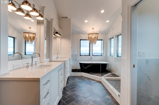 bathroom with a bathtub, tile walls, vanity, an inviting chandelier, and vaulted ceiling