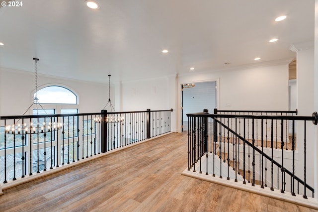 hallway with a notable chandelier, light hardwood / wood-style floors, and crown molding