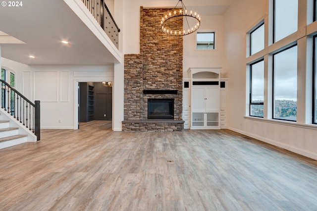 unfurnished living room with light hardwood / wood-style flooring, a stone fireplace, and plenty of natural light